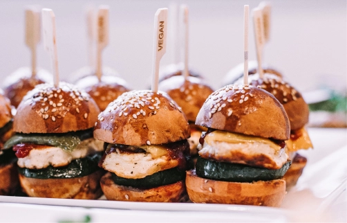 vegan burger patties drenched in souce served on a white platter pierced with wooden toothpick